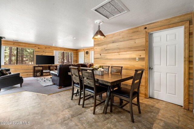 dining space featuring carpet flooring and wooden walls