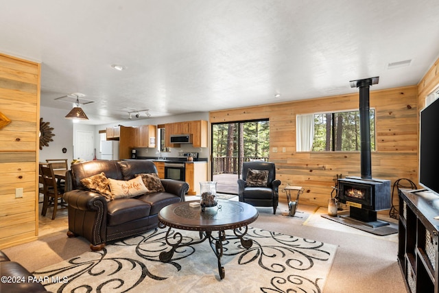 living room featuring wood walls, light colored carpet, and a wood stove