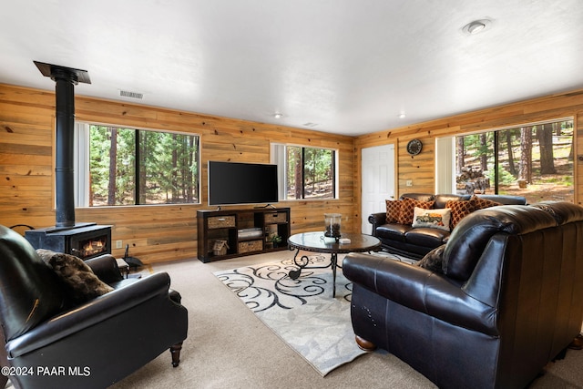 living room featuring a wood stove, wooden walls, and light colored carpet