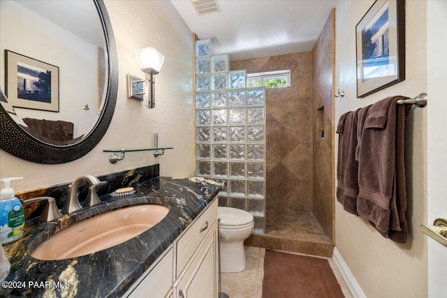 bathroom with tile patterned floors, a textured ceiling, toilet, tiled shower, and vanity