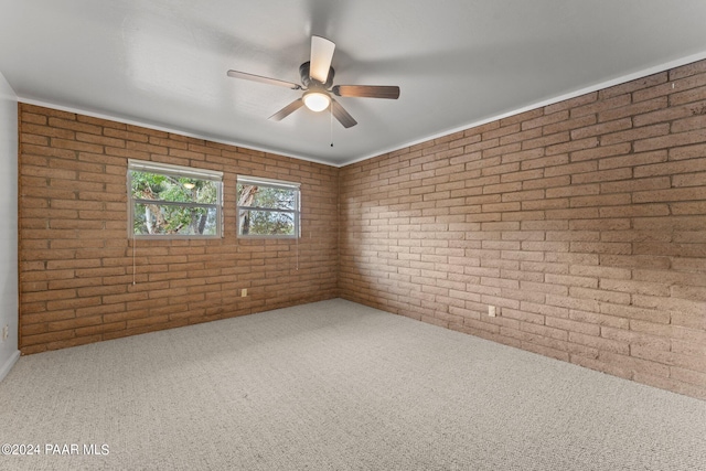 empty room with ceiling fan, carpet floors, and brick wall