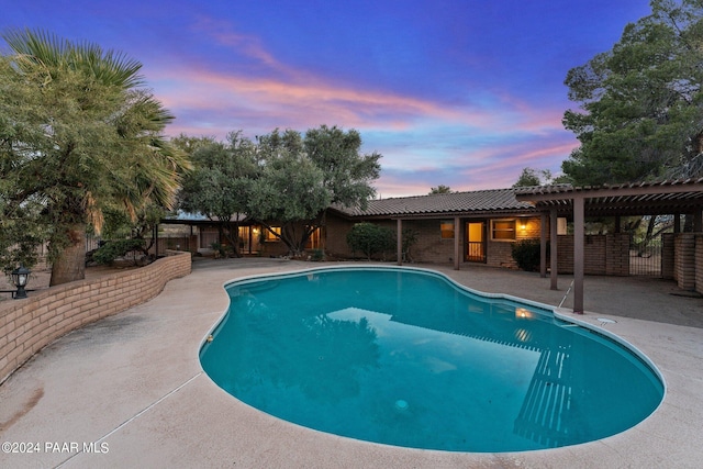 pool at dusk featuring a pergola and a patio