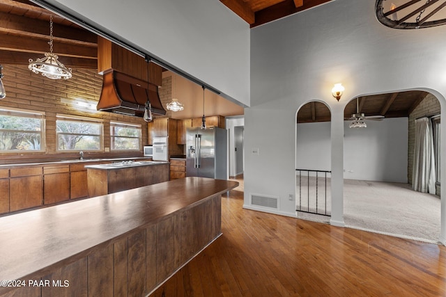 kitchen featuring hardwood / wood-style floors, high end fridge, high vaulted ceiling, and pendant lighting