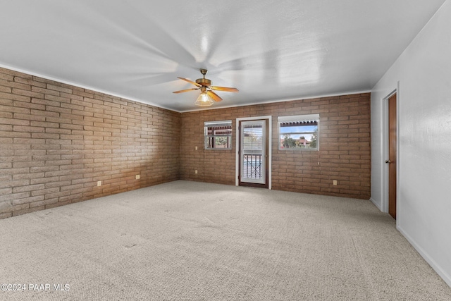 spare room with carpet, ceiling fan, and brick wall