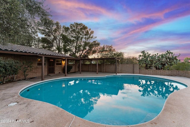 pool at dusk featuring a patio area