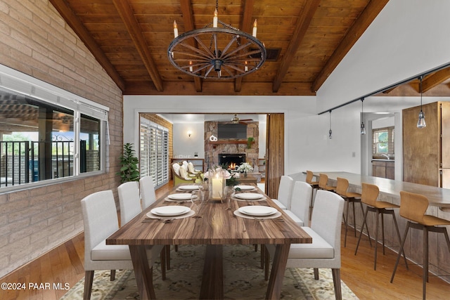 dining area with vaulted ceiling with beams, light hardwood / wood-style floors, wood ceiling, and brick wall