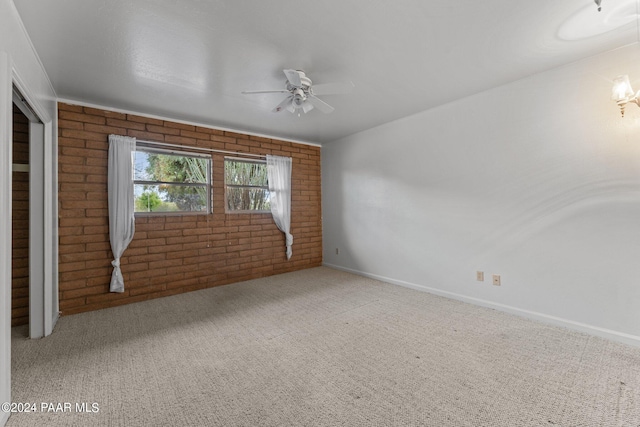 empty room with light colored carpet, ceiling fan, and brick wall