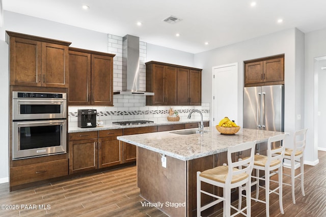 5357 Crescent Edge Dr, Prescott, AZ 86301 - kitchen with wall chimney exhaust hood, a sink, stainless steel appliances, light wood-style floors, and a center island with sink