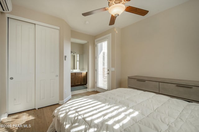 bedroom with a closet, an AC wall unit, ceiling fan, and light hardwood / wood-style floors