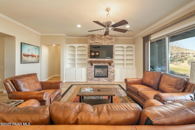 living room with hardwood / wood-style flooring, ceiling fan, built in features, a fireplace, and ornamental molding