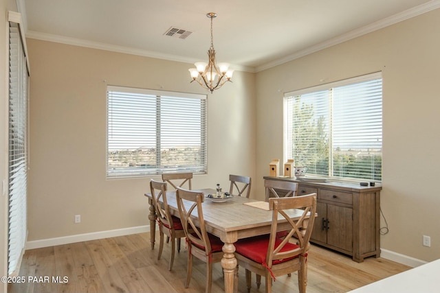 dining area with light hardwood / wood-style floors, crown molding, and a notable chandelier