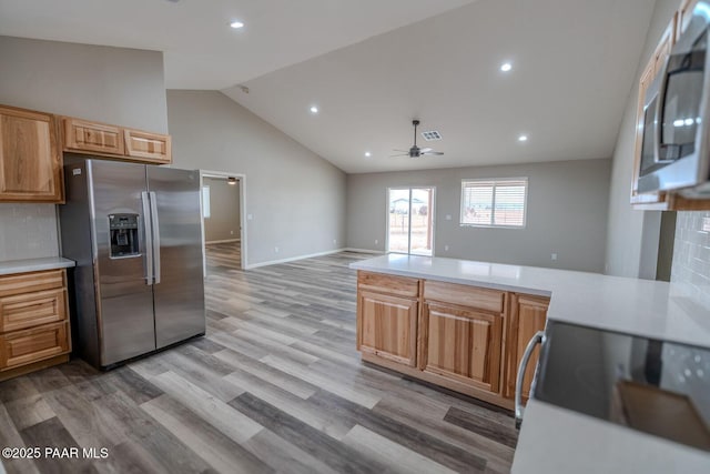 kitchen featuring ceiling fan, appliances with stainless steel finishes, high vaulted ceiling, tasteful backsplash, and light hardwood / wood-style floors