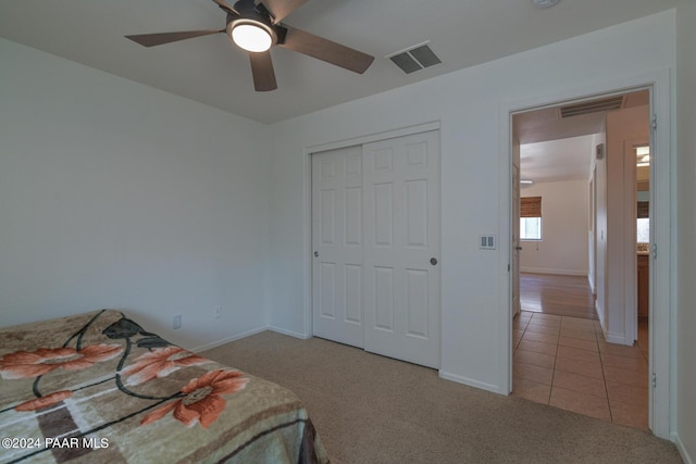 carpeted bedroom with ceiling fan and a closet