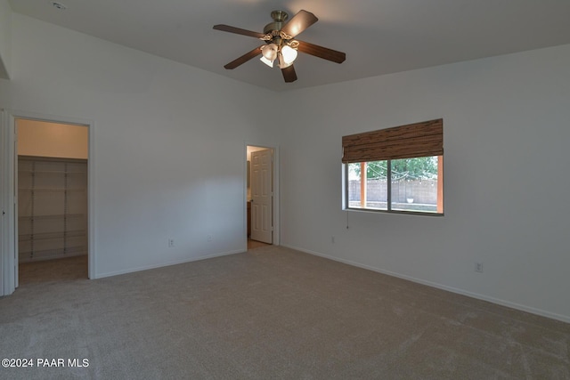 unfurnished bedroom with carpet flooring, ceiling fan, a walk in closet, and a closet