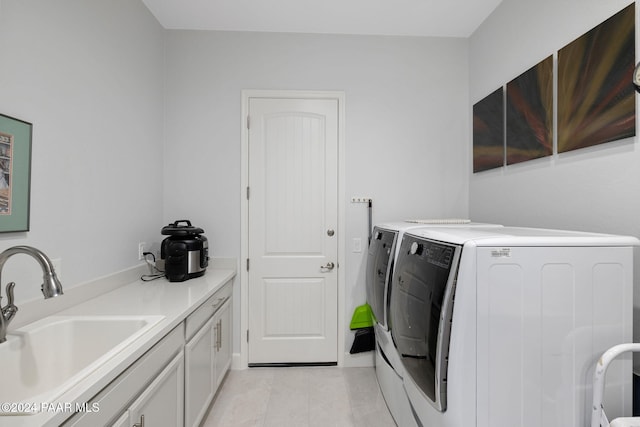 washroom with cabinets, light tile patterned floors, washer and clothes dryer, and sink