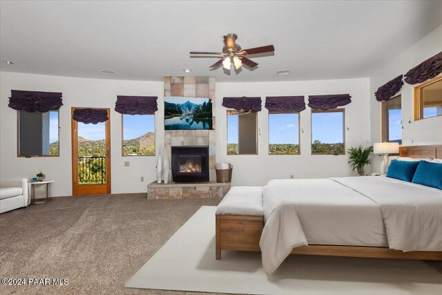 bedroom featuring visible vents, carpet, a tiled fireplace, and access to outside