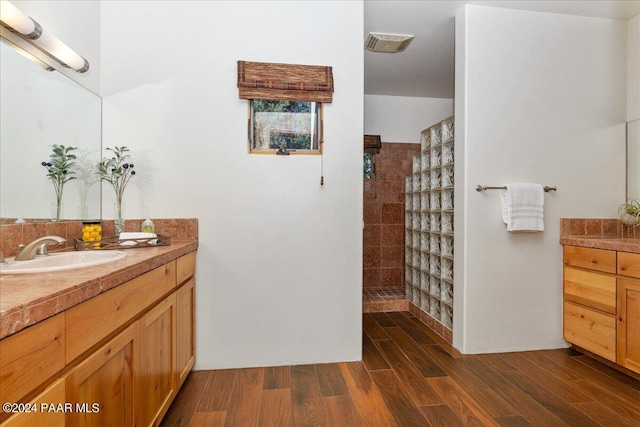 bathroom with visible vents, vanity, walk in shower, and wood finished floors