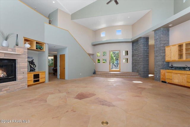 living area featuring high vaulted ceiling, a fireplace, indoor wet bar, stairs, and stone finish flooring