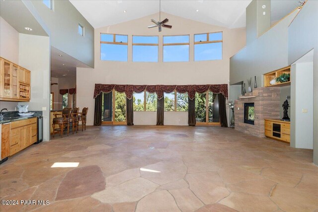 unfurnished living room featuring visible vents, vaulted ceiling, a fireplace, a ceiling fan, and a sink