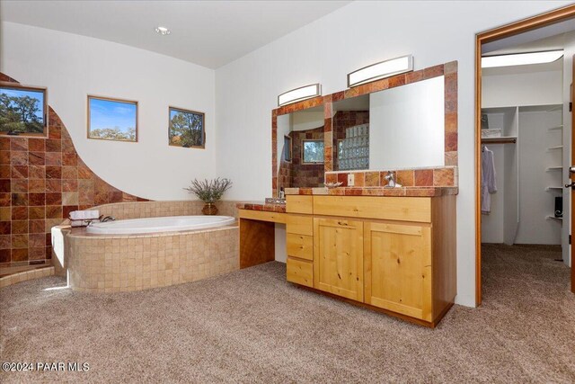 bathroom with vanity and tiled tub