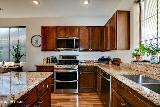 kitchen featuring stainless steel appliances, light stone countertops, and light hardwood / wood-style flooring