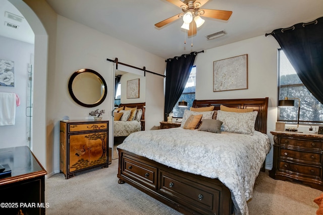 carpeted bedroom featuring ceiling fan and a barn door