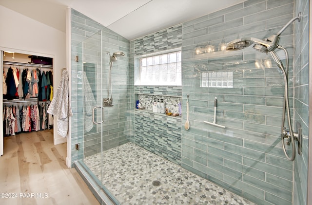 bathroom featuring a shower with shower door, lofted ceiling, and tile walls