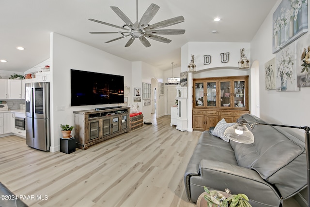 living room featuring ceiling fan, vaulted ceiling, and light wood-type flooring