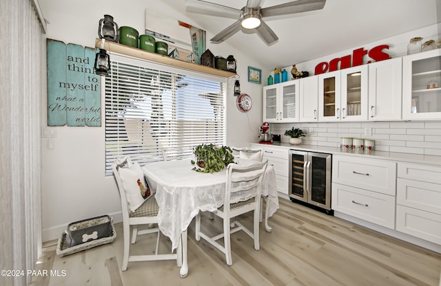 kitchen with lofted ceiling, backsplash, light hardwood / wood-style flooring, white cabinetry, and beverage cooler