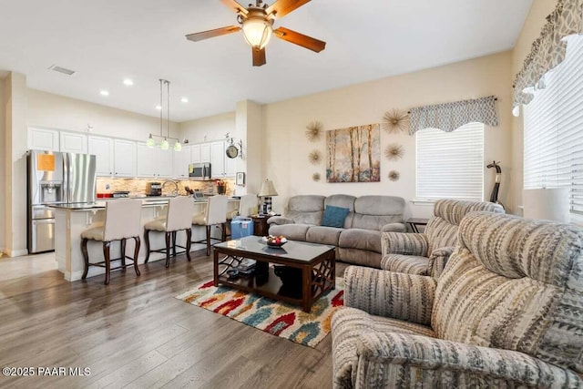 living room featuring ceiling fan and dark hardwood / wood-style flooring