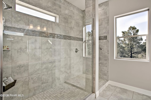bathroom featuring baseboards, tiled shower, and marble finish floor