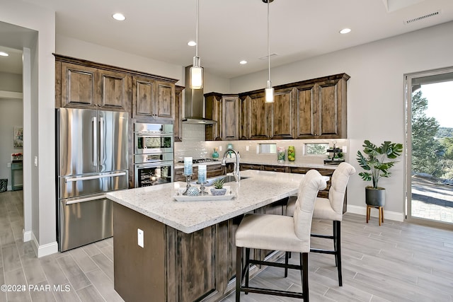 kitchen featuring light stone counters, appliances with stainless steel finishes, visible vents, light wood-style floors, and backsplash