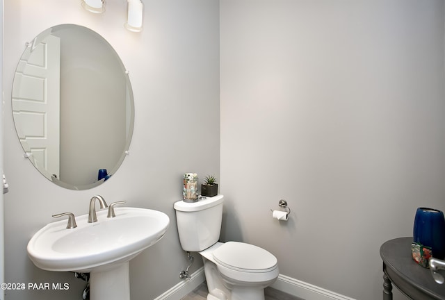 bathroom with a sink, toilet, and baseboards