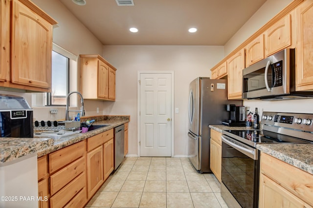 kitchen featuring sink, light stone counters, light brown cabinetry, light tile patterned floors, and appliances with stainless steel finishes