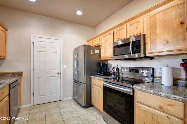 kitchen featuring dark stone countertops, light tile patterned floors, stainless steel appliances, and light brown cabinetry