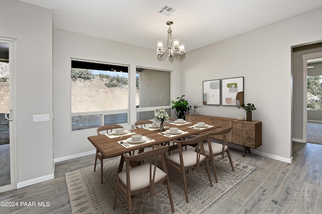 dining space with a chandelier, baseboards, visible vents, and wood finished floors