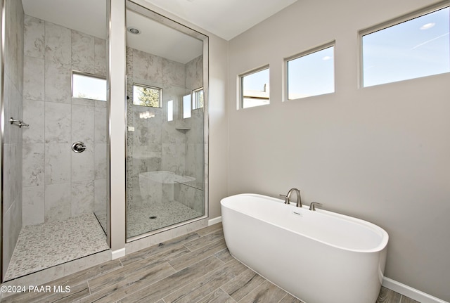 bathroom with plenty of natural light, a tile shower, a soaking tub, and wood tiled floor