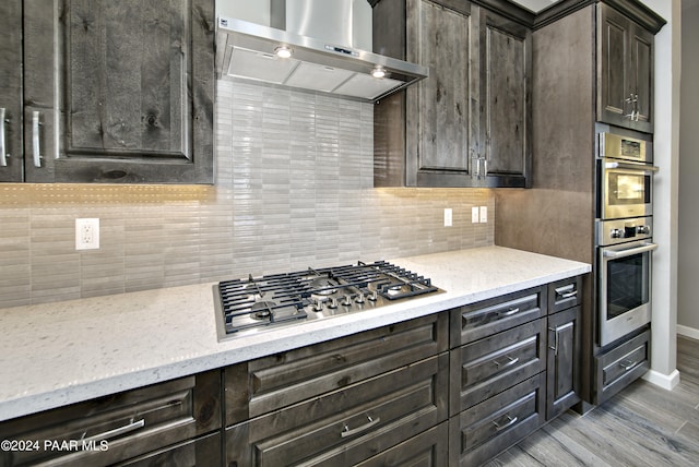 kitchen with backsplash, appliances with stainless steel finishes, dark brown cabinets, baseboards, and extractor fan