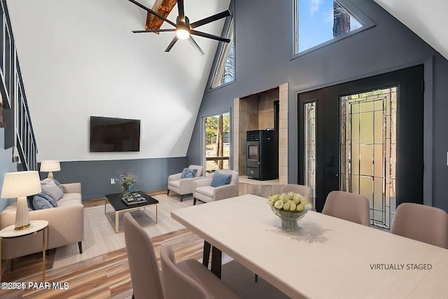 dining room featuring wood-type flooring, ceiling fan, and a high ceiling