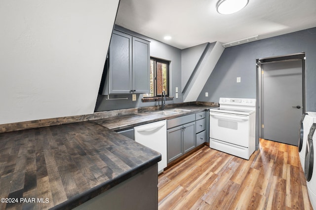 kitchen with sink, gray cabinetry, white appliances, and light hardwood / wood-style floors