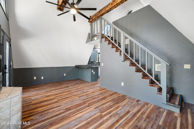 unfurnished living room with ceiling fan, a towering ceiling, and dark hardwood / wood-style flooring