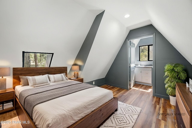 bedroom featuring vaulted ceiling, connected bathroom, and hardwood / wood-style floors