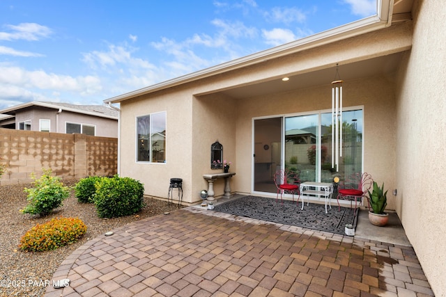 rear view of house featuring stucco siding, a patio area, and fence