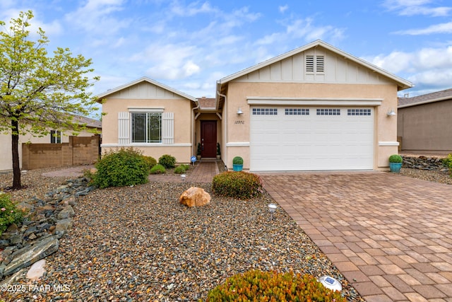 ranch-style house featuring fence, driveway, an attached garage, stucco siding, and board and batten siding
