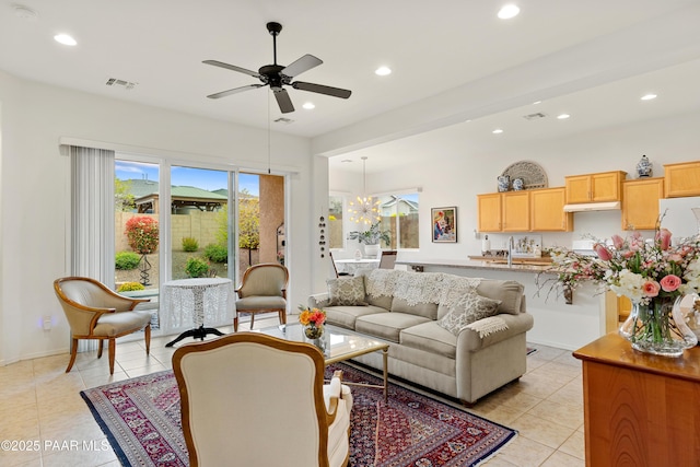 living room with light tile patterned floors, recessed lighting, a ceiling fan, baseboards, and a chandelier