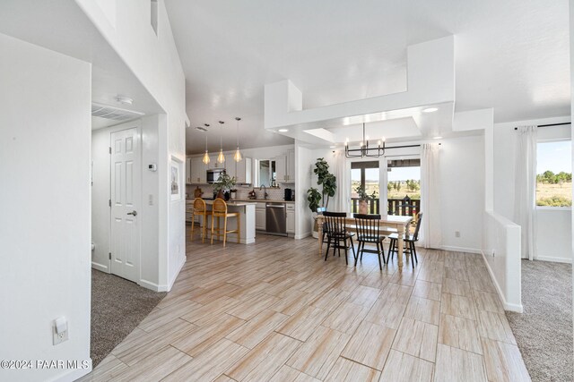 carpeted dining room featuring a wealth of natural light, sink, and a notable chandelier