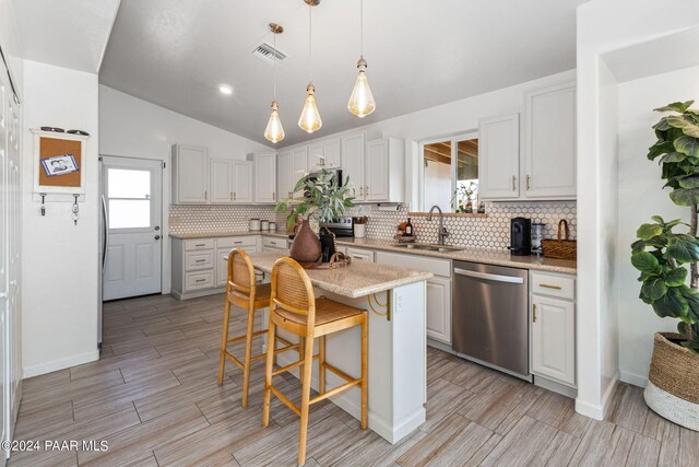 kitchen featuring dishwasher, lofted ceiling, white cabinets, sink, and a kitchen island