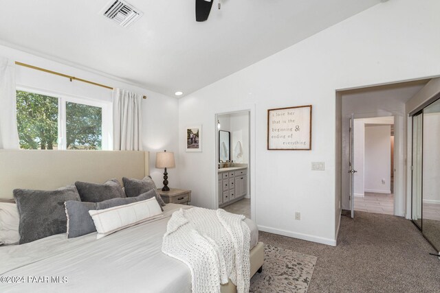 bedroom with ensuite bathroom, ceiling fan, light colored carpet, and vaulted ceiling