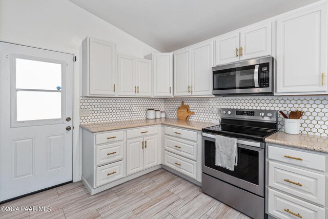 kitchen featuring white cabinets, backsplash, stainless steel appliances, and lofted ceiling