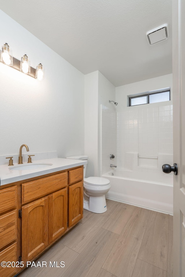 full bathroom featuring tiled shower / bath combo, vanity, hardwood / wood-style floors, and toilet